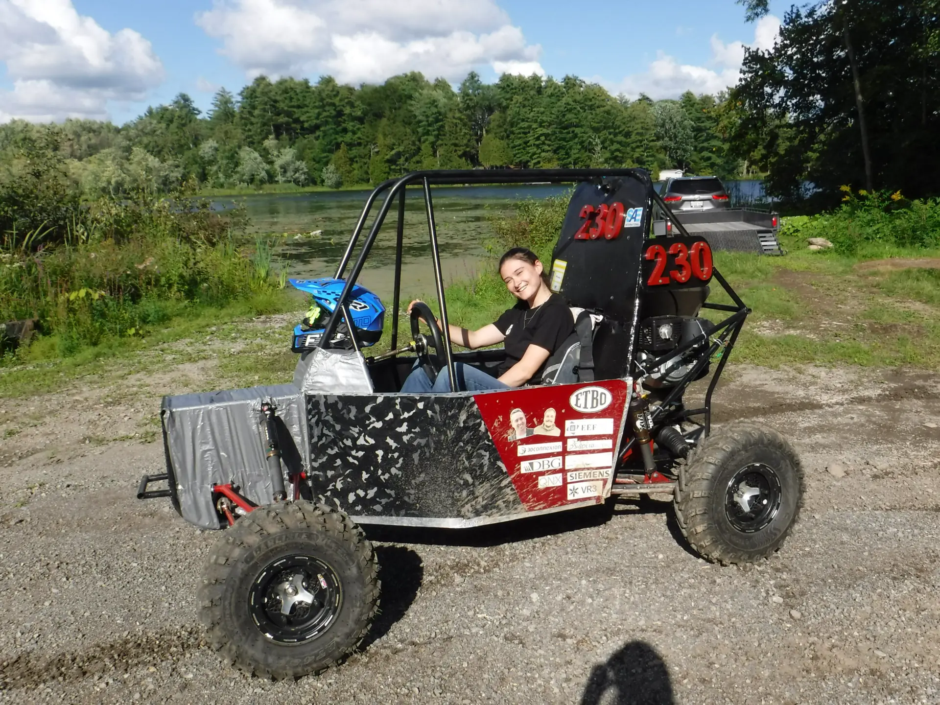 Team member smiling from the driver's seat of car #230