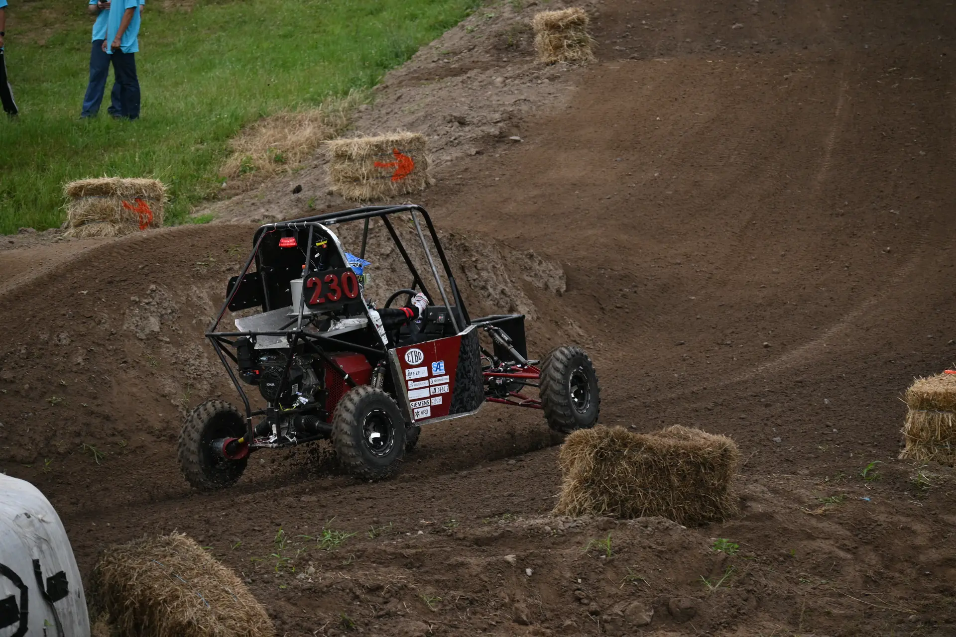 Car #230 climbing a berm on the course, suspension working over the dirt