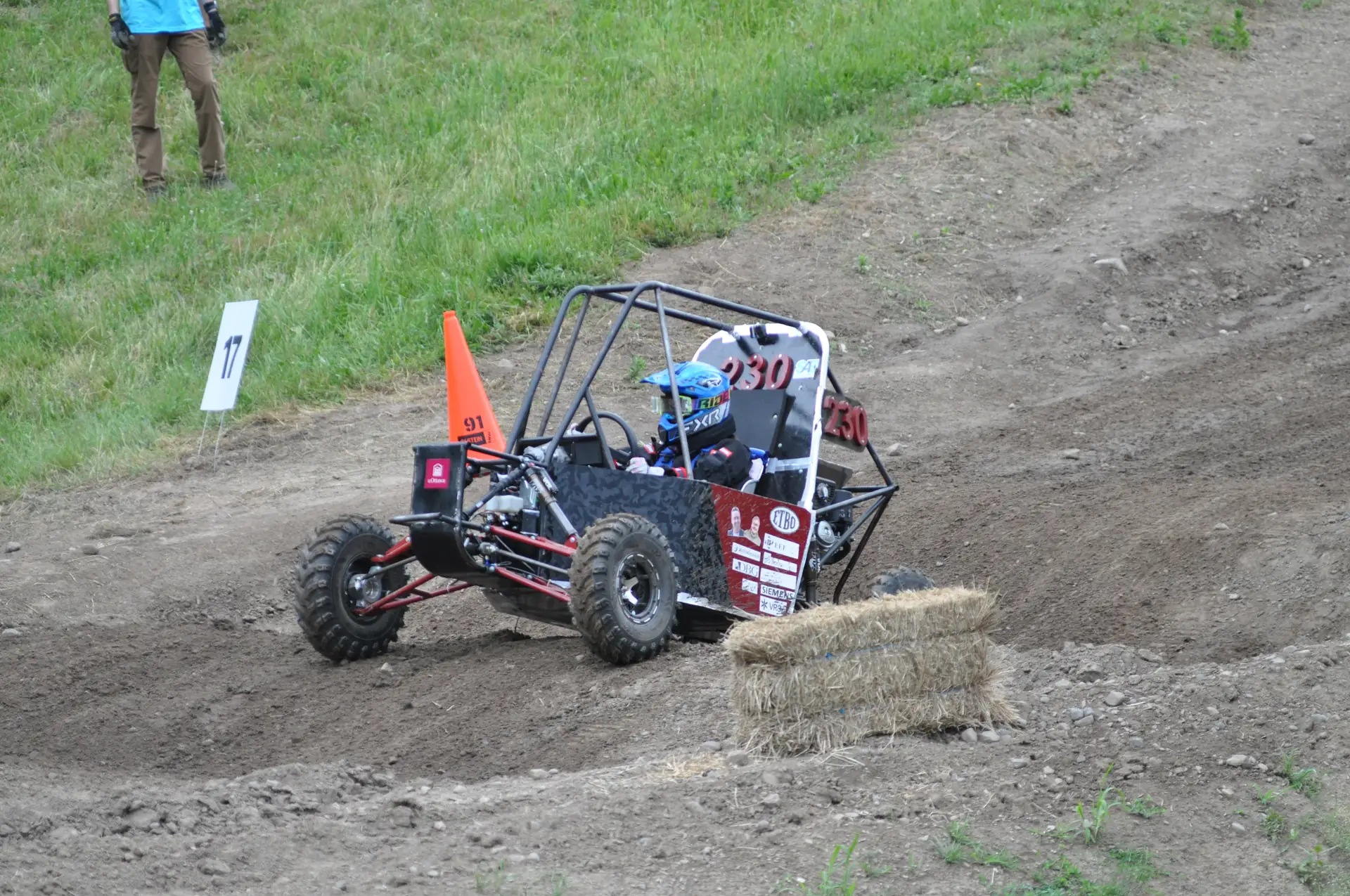 Car #230 climbing a banked turn past a hay bale