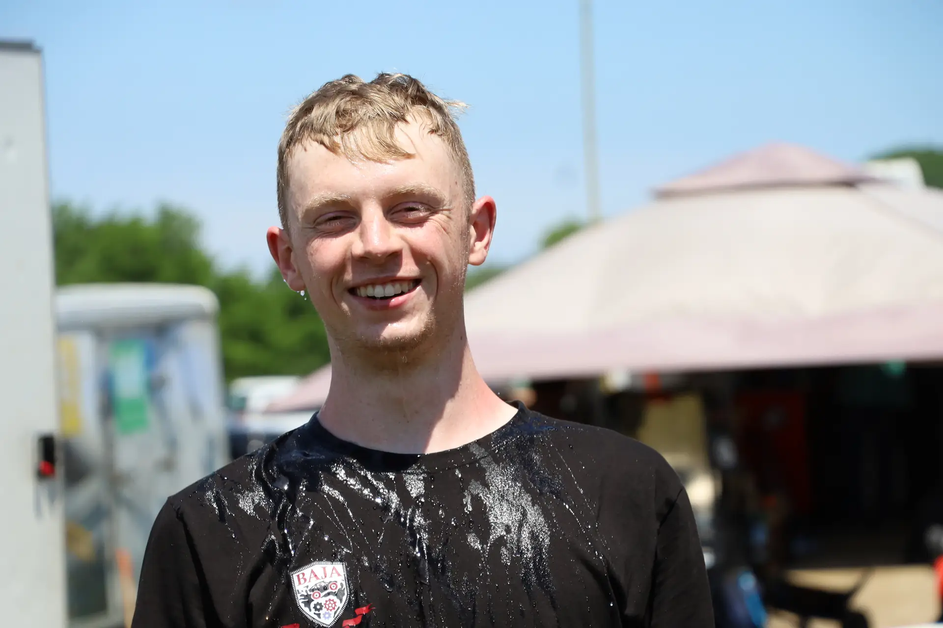 Team member grinning in a mud-splattered team shirt