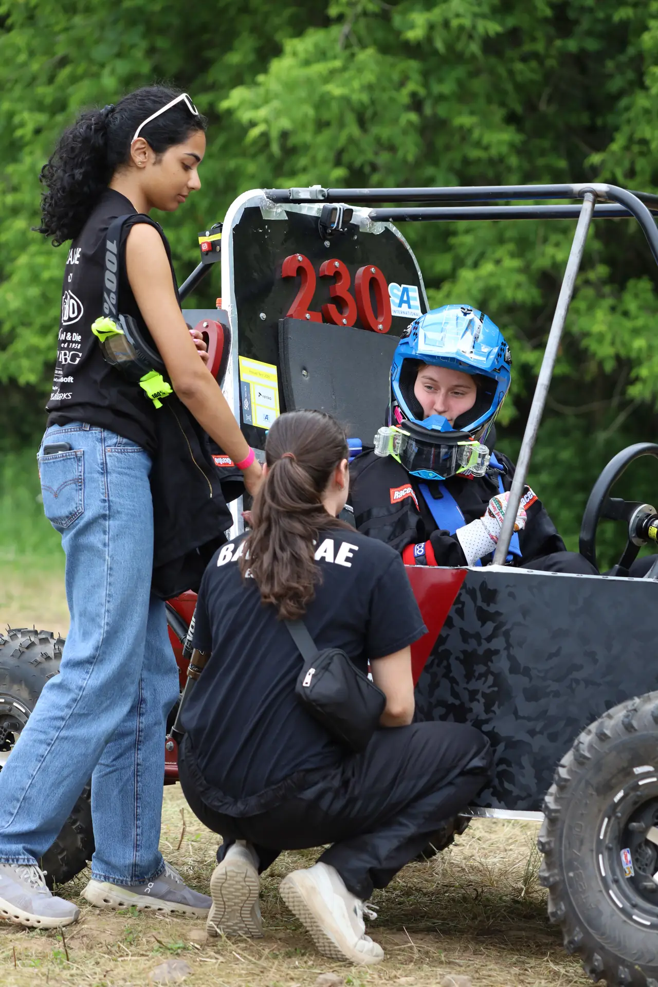 Team members helping the driver strap in