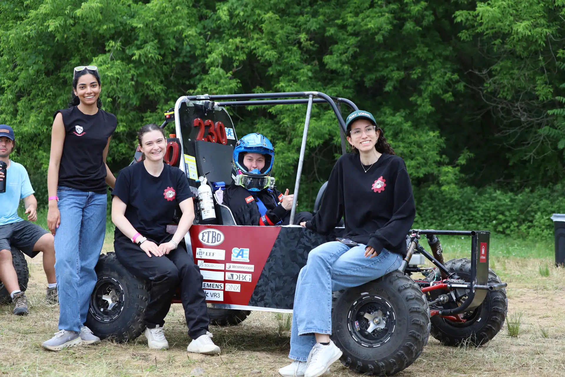 Team members posing with the car and its driver at competition